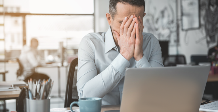 Man in front of laptop with hands on his face