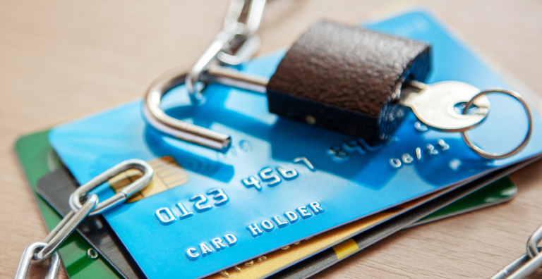 Unlocked padlock resting on stack of credit cards