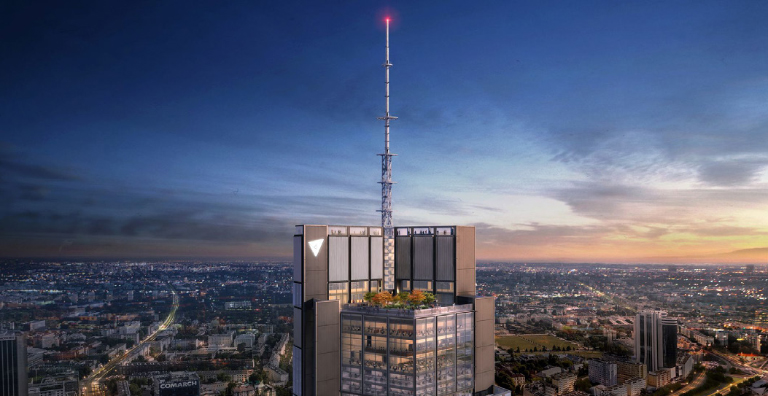 An ariel view of a tall commercial building looking over a city at dusk.