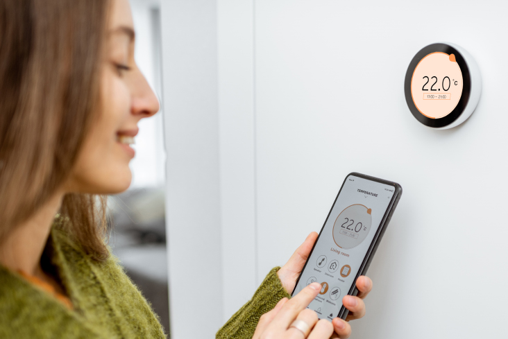 A person using their phone to control an indoor thermometer