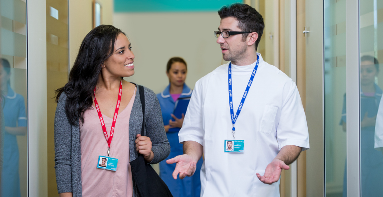 Two hospital visitors wearing Visitor Management badges