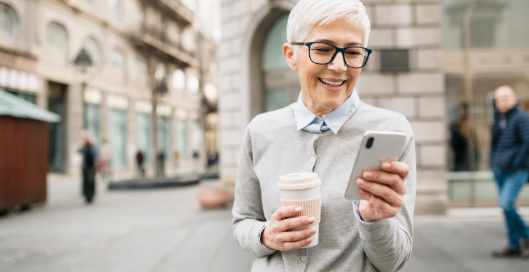 person holding coffee and looking at phone