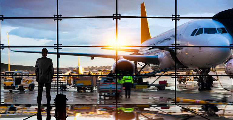 person standing in airport looking at plane